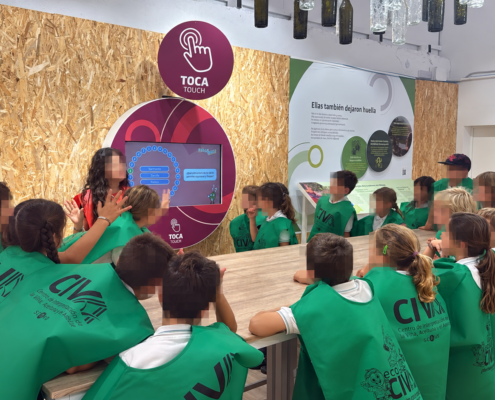 Escolares tocan una pantalla interactiva sobre el aceite de orujo de oliva en el museo interactivo del CIVA